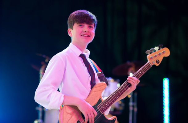 smiling school boy performing guitar