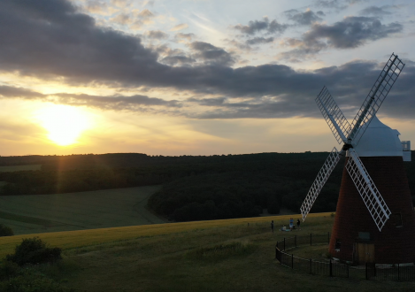 windmill in a field with the sun setting