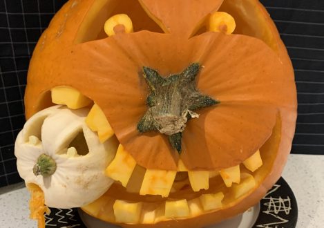 A pumpkin carving where it's eating another smaller gourd as part of the carving