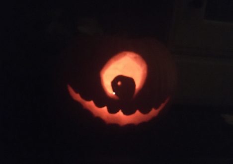 A carving of a one-eyed monster in the center of a pumpkin