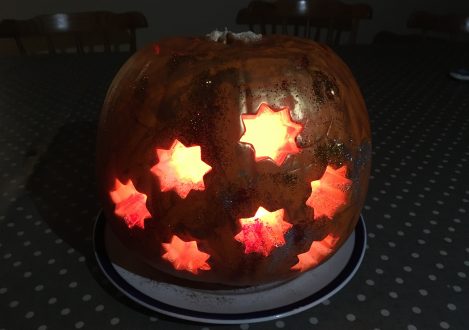 A pumpkin carved with stars in the middle and lit up from the inside