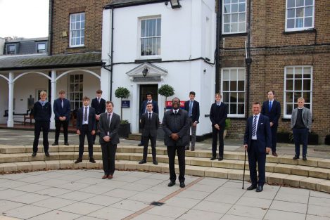 A row of teachers and another row of students socially distancing within the Halliford School grounds