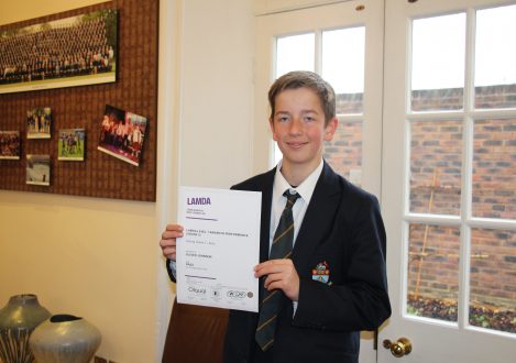 School boy holding LAMDA Examination Certificate