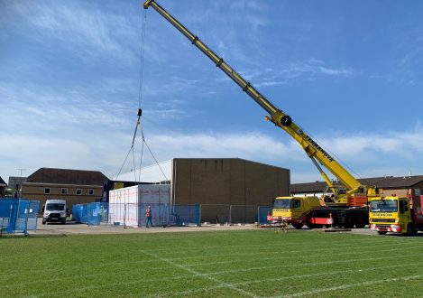 Crane helping men build a school