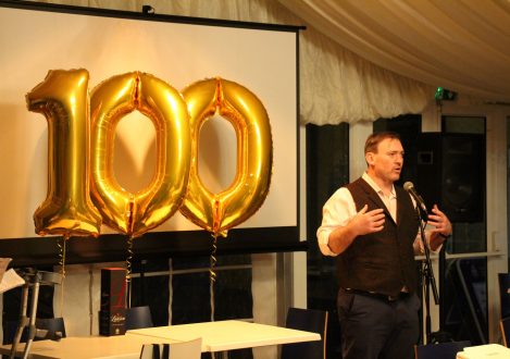 man standing next to 100 ballon