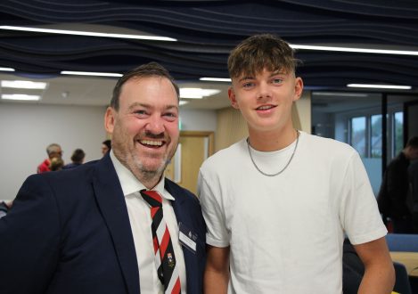 Child standing and smiling with his teacher