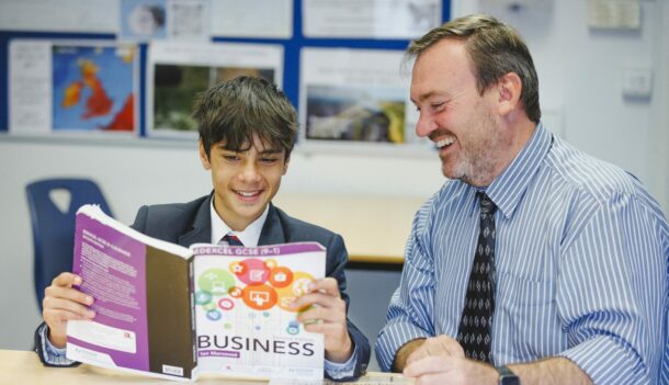 student holding a business text book and reading to teacher