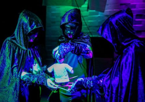 three boys stood in a circle wearing black cloaks