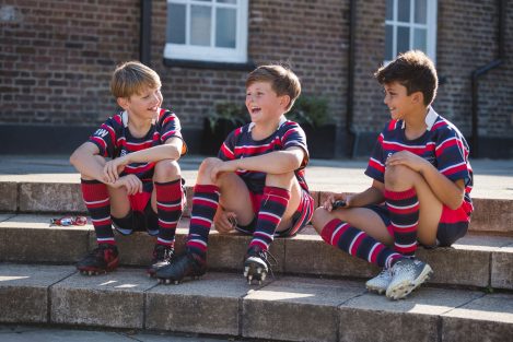 3 boys happily sat on a step after a sports game