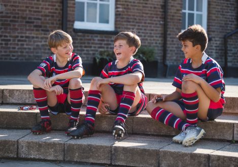 3 boys happily sat on a step after a sports game