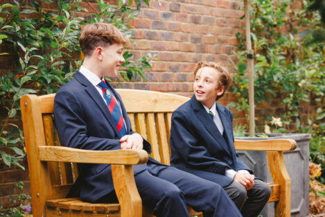 2 students, of different ages, sat on a bench