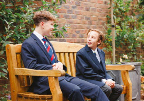 2 students, of different ages, sat on a bench