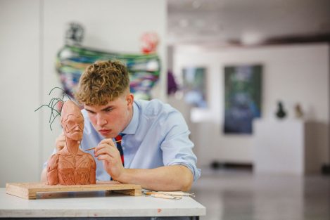 student touching up a clay model