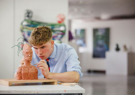 student touching up a clay model