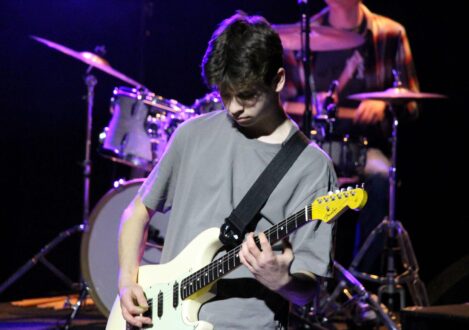 student playing the guitar in a band