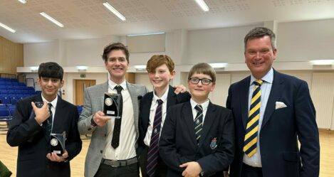 students and teachers holding debate competition trophies