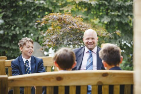 teacher and students sat on a bench